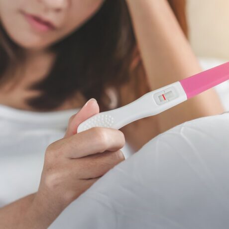 Femeie cu menstruație întârziată și test negativ de sarcină în mână